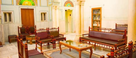 A traditional interior with ornate furniture, a central coffee table, and a bookshelf.
