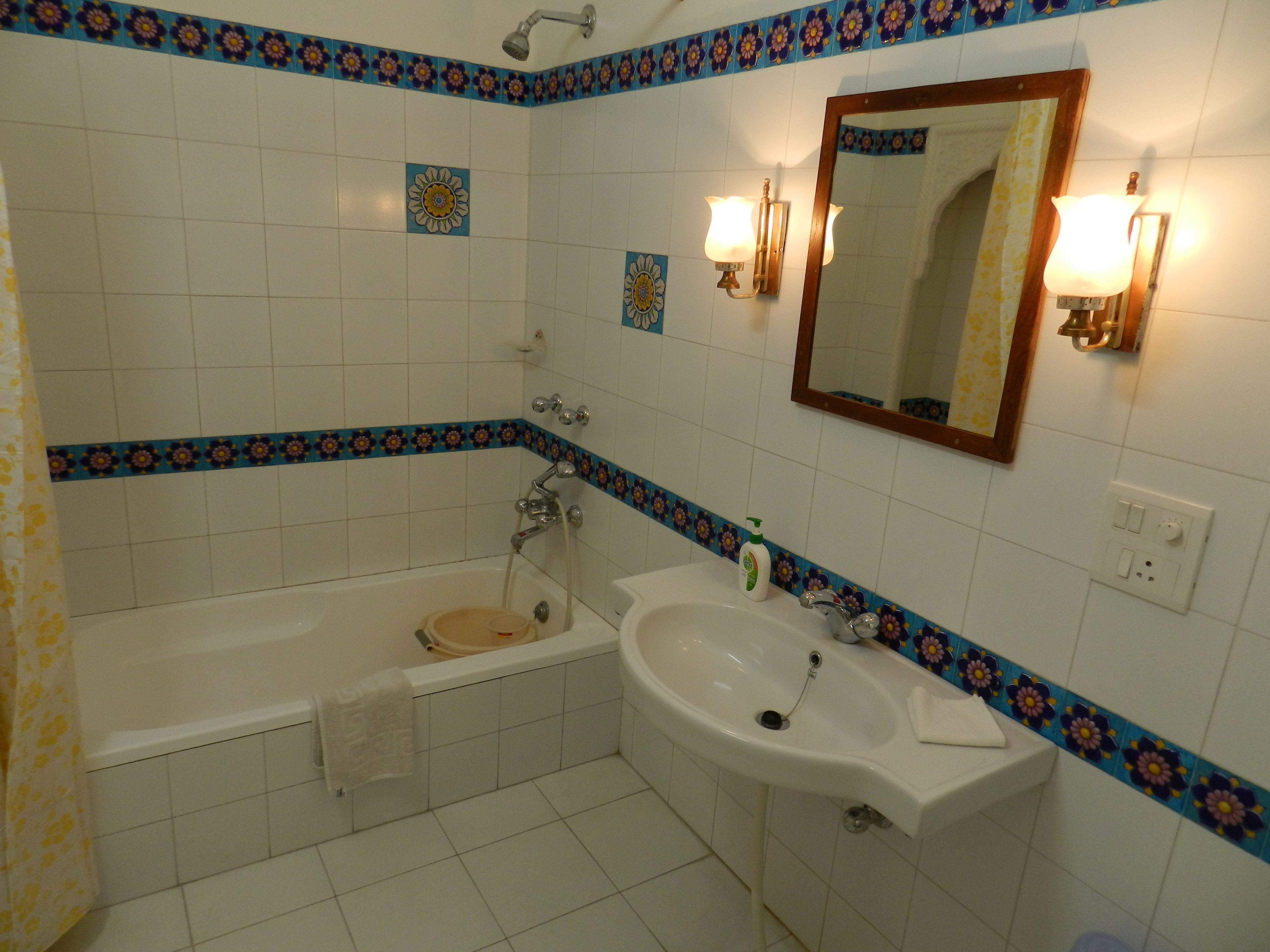 Une salle de bain avec une baignoire, un lavabo, un miroir et des carreaux décoratifs.