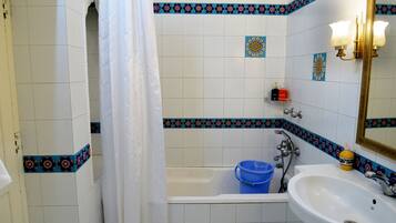 A bathroom with a bathtub, a sink, and a shower curtain.