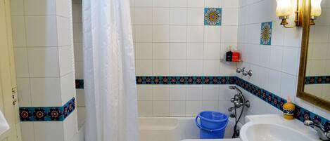 Un baño con bañera, lavabo y cortina de ducha.