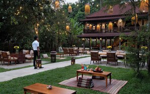 An outdoor seating area with tables and chairs, surrounded by greenery and string lights. - The Community - Siem Reap (Siem Reap)