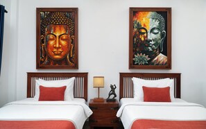 A hotel room with two beds, a nightstand with a lamp, and two Buddha paintings on the wall. - The Community - Siem Reap (Siem Reap)