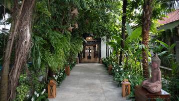 Un sendero bordeado de faroles y plantas tropicales que conduce a la entrada de un edificio.