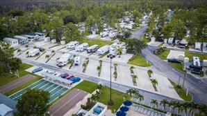 A campground with RVs, a pool, and a tennis court. - Club Naples RV Resort (Naples)