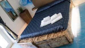 A bed with a blue wave design on the ceiling, a wooden headboard, and a dark blue bedspread with a pattern. - Soggiorno Sogna Firenze (Florence)