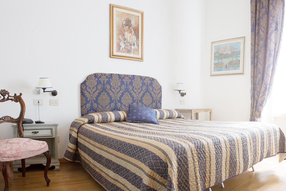 A room with a bed, a chair, a desk, and a door.