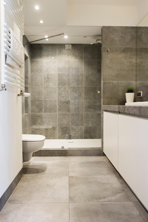 A modern bathroom with a shower, toilet, and sink.