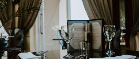 Une table dressée pour le repas, avec un menu, deux verres à vin et des couverts.