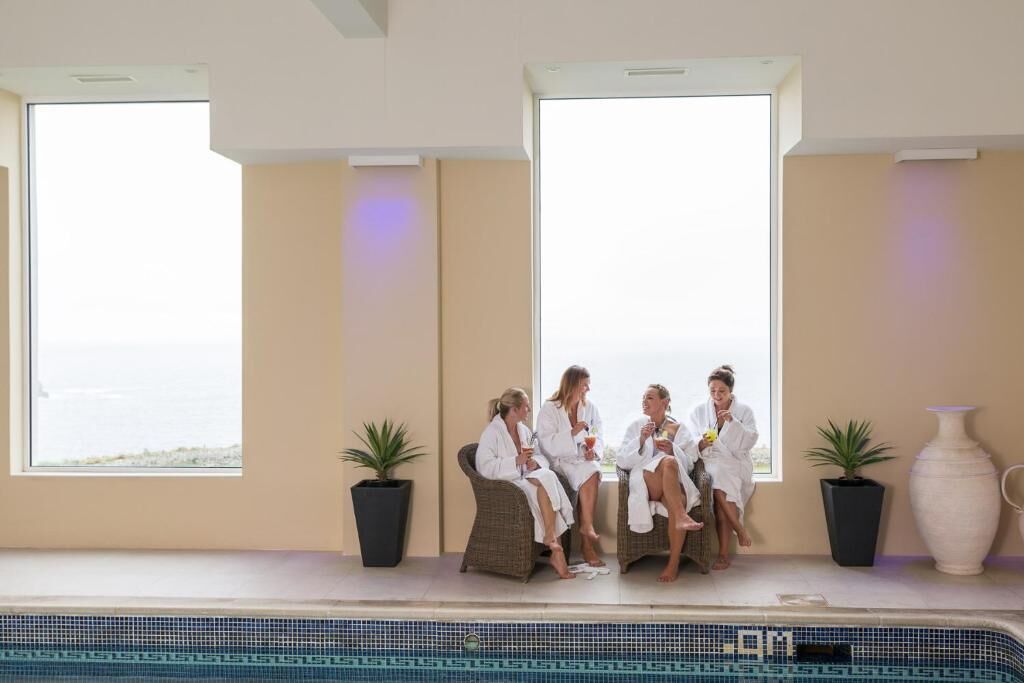A poolside area with a view of the sea, potted plants, and a large vase.