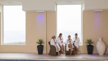 A poolside area with a view of the sea, potted plants, and a large vase.