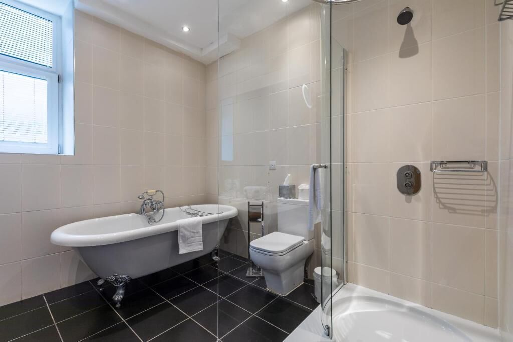 Une salle de bain moderne avec une baignoire sur pieds, une douche à parois de verre et des toilettes.