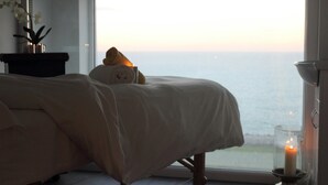 A bedroom with a large window, a bed, a nightstand, and a candle. - The Atlantic Hotel (Newquay)