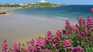A coastal beach with a clear view of the sea, a sandy shore, and buildings in the background. - The Atlantic Hotel (Newquay)