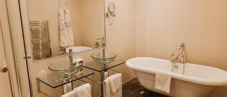 Ein Badezimmer mit einem separaten Waschbecken, einer freistehenden Badewanne und einem Spiegel über dem Waschbecken.