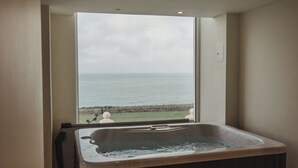 A modern bathroom with a large bathtub, a view of the ocean, and a step stool. - The Atlantic Hotel (Newquay)