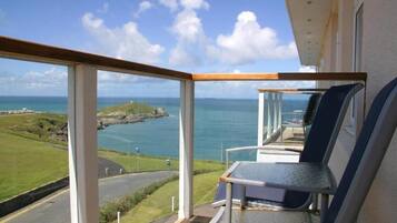 A balcony with a view of the sea and a grassy area.