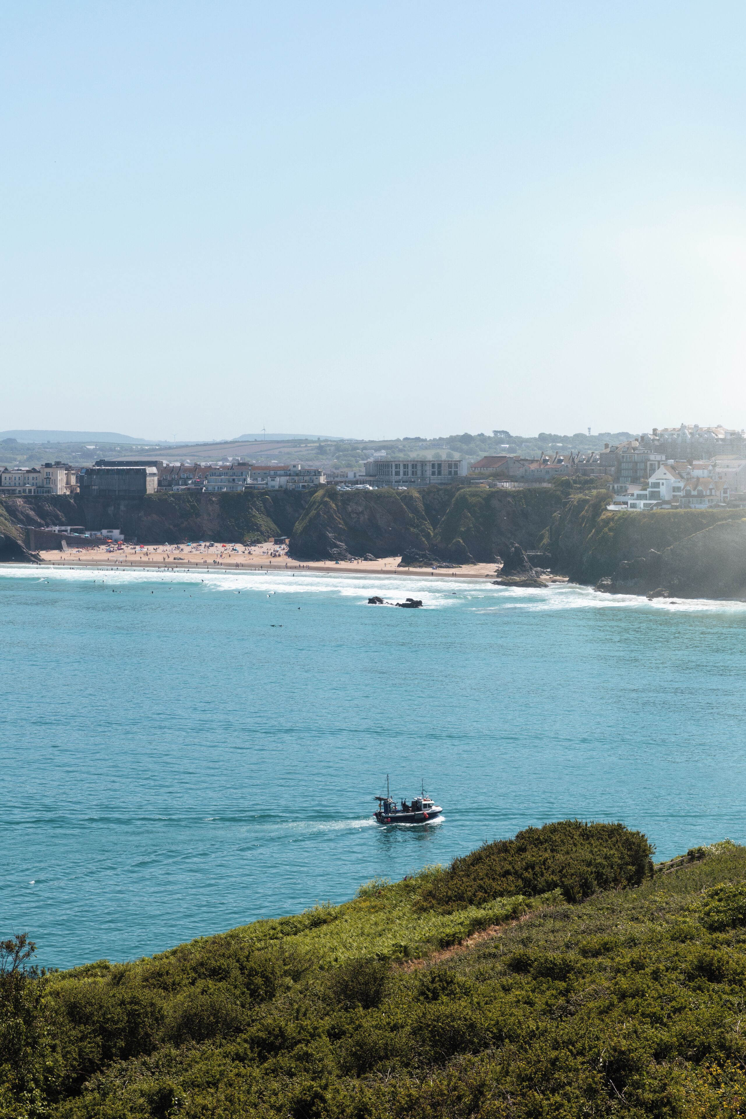 A coastal town with a beach, a boat in the water, and buildings in the background.