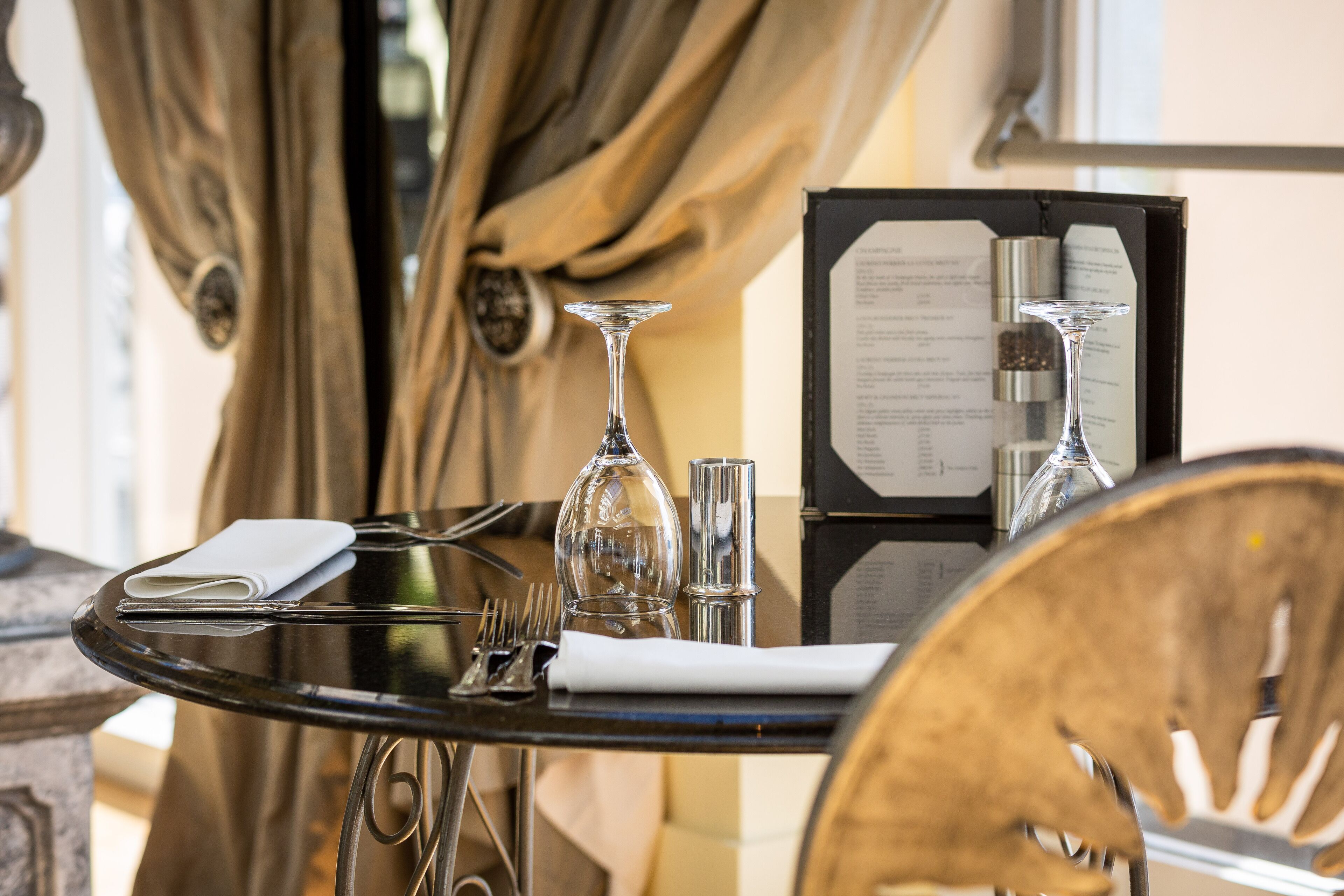 A dining table set with a menu, a wine glass, and a folded napkin.