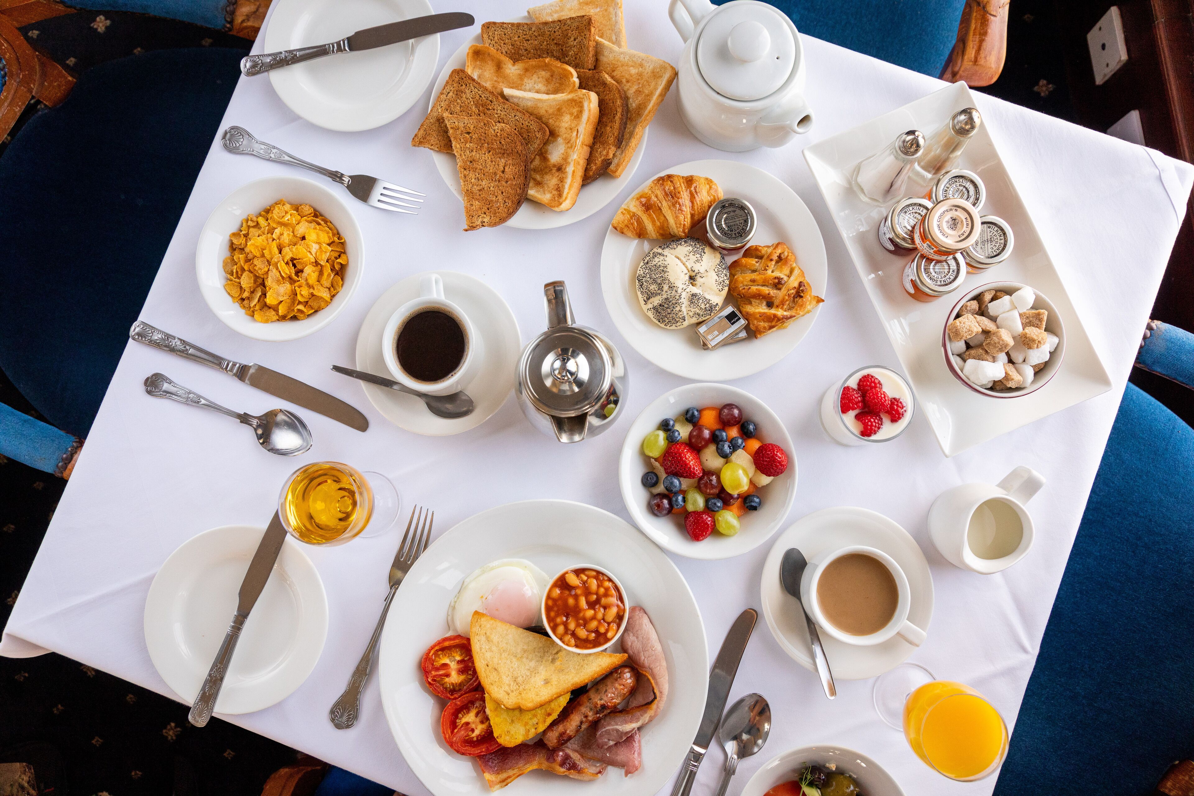 Uma mesa de café da manhã com diversos alimentos e utensílios.