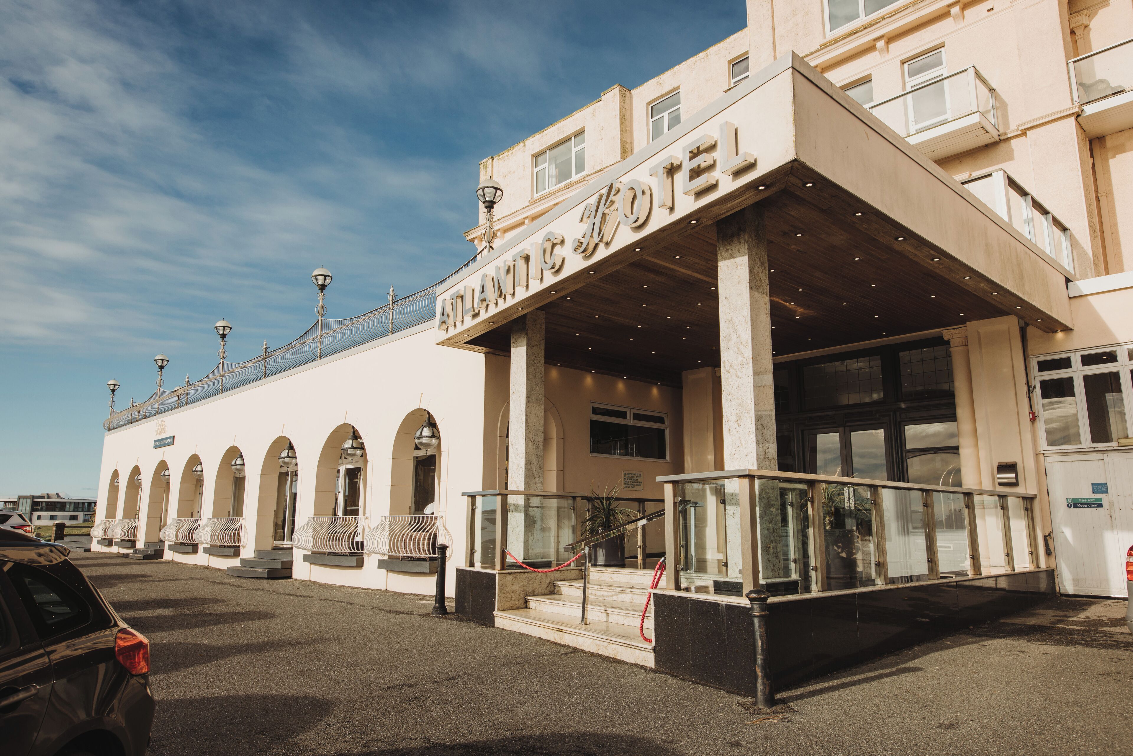 Un hotel con un letrero llamativo, un acceso cubierto y una serie de ventanas arqueadas.