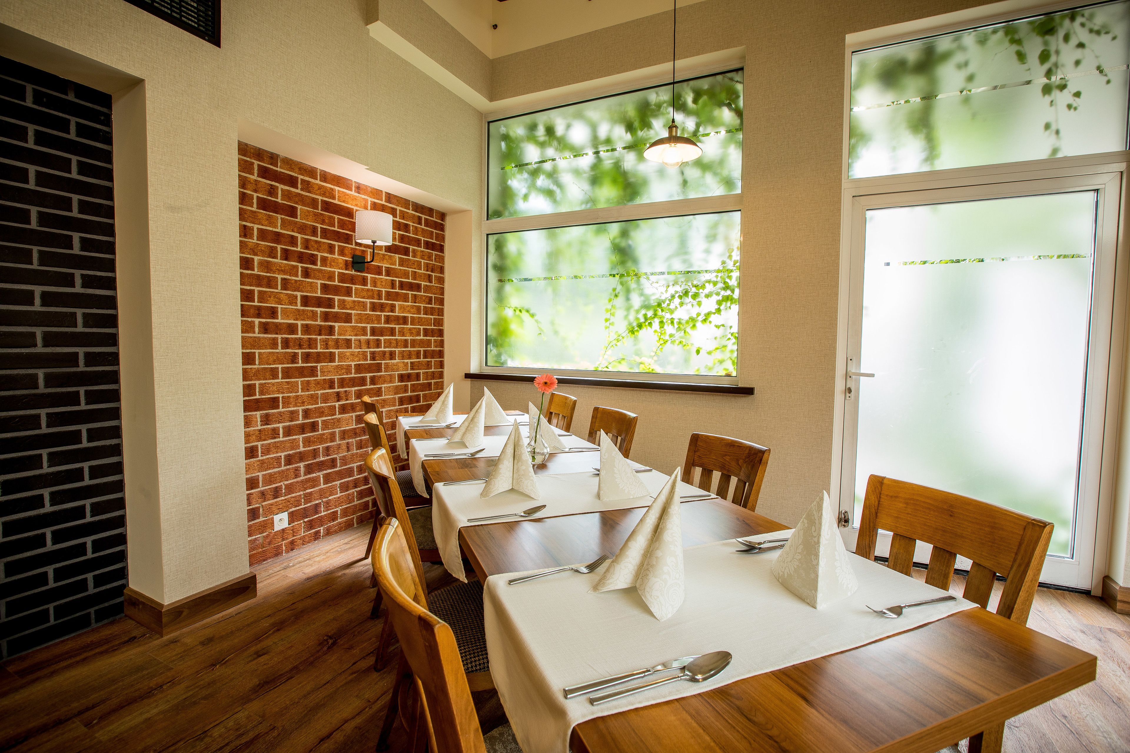 A dining area with wooden tables, white tablecloths, and napkins.