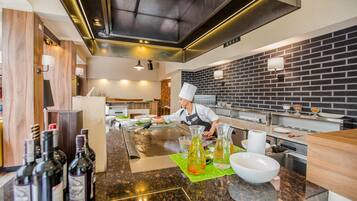 A modern kitchen with a chef preparing food, a brick wall, and various cooking utensils and ingredients.