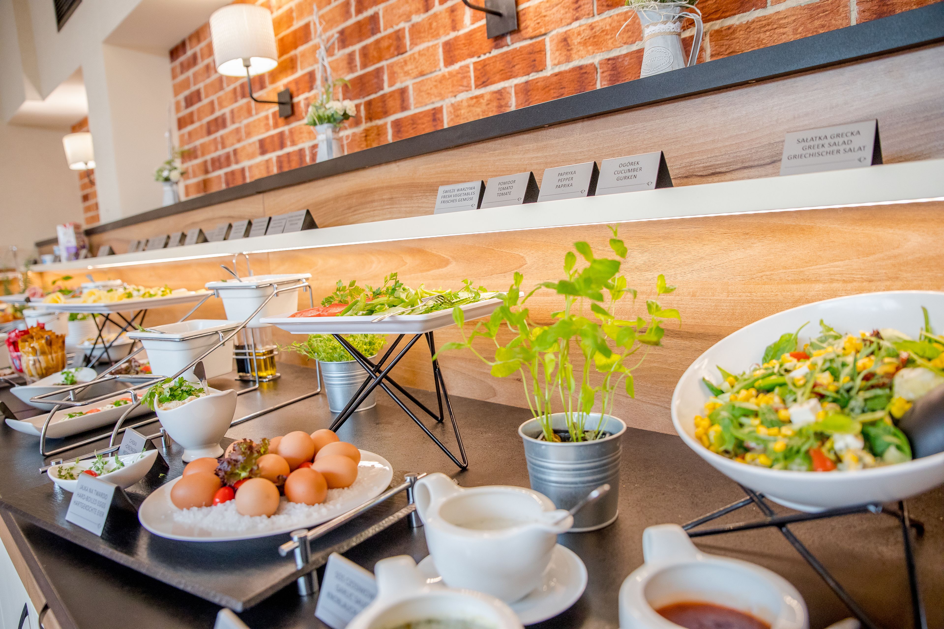 A buffet with various dishes and a brick wall background.