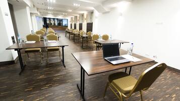 A conference room with multiple tables and chairs, equipped with laptops and water bottles.