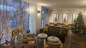 Een moderne woonkamer met een bank, fauteuils, een salontafel en een kerstboom.