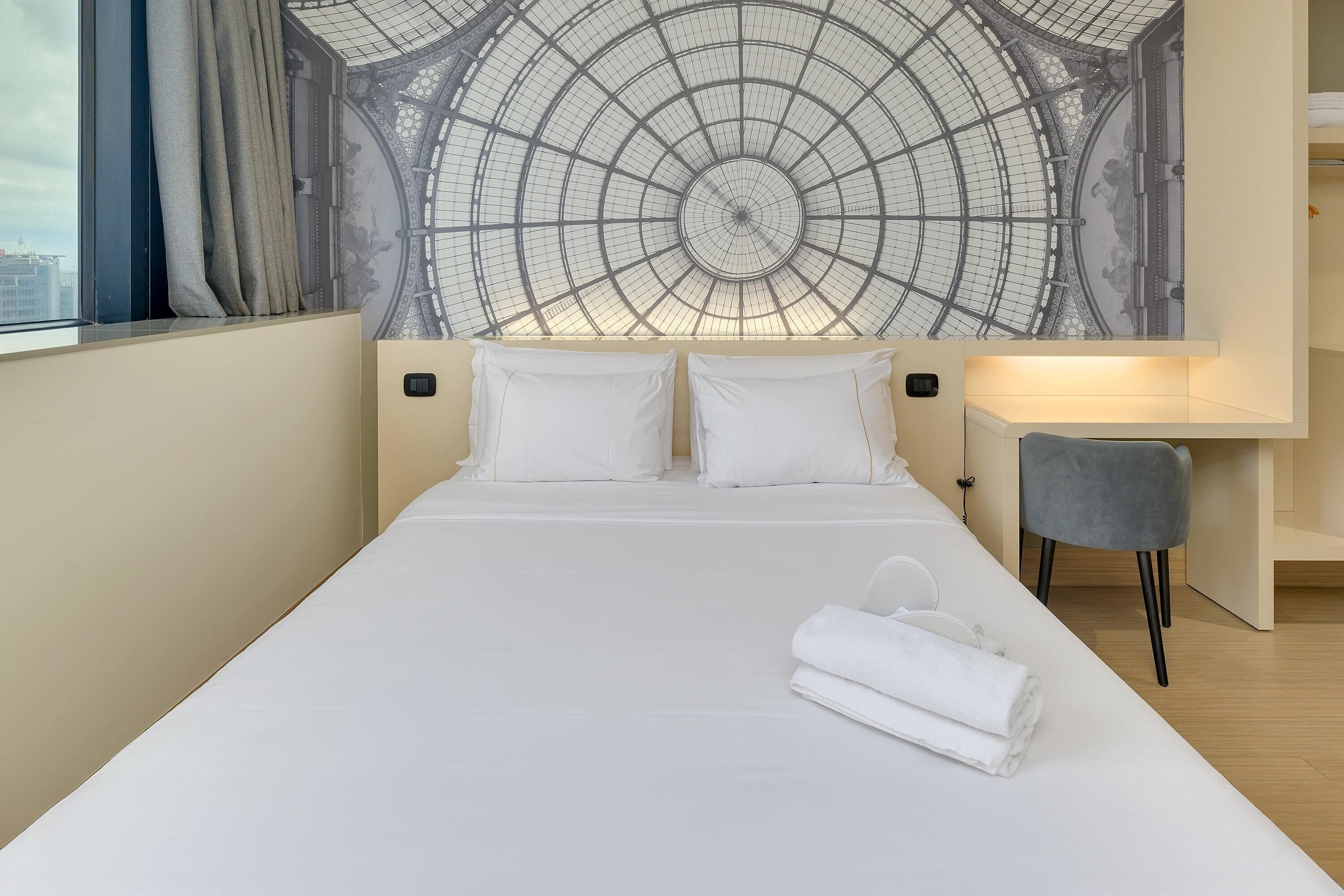 Una camera d'albergo con un letto grande, una scrivania e una sedia.