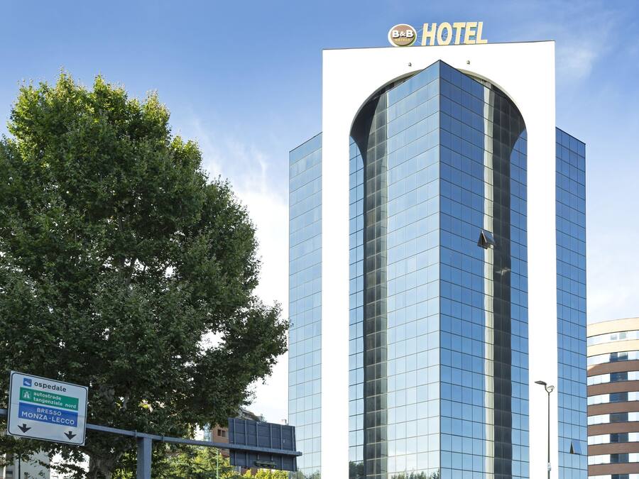 A modern hotel building with a curved glass facade and a sign indicating it is a B&B hotel.
