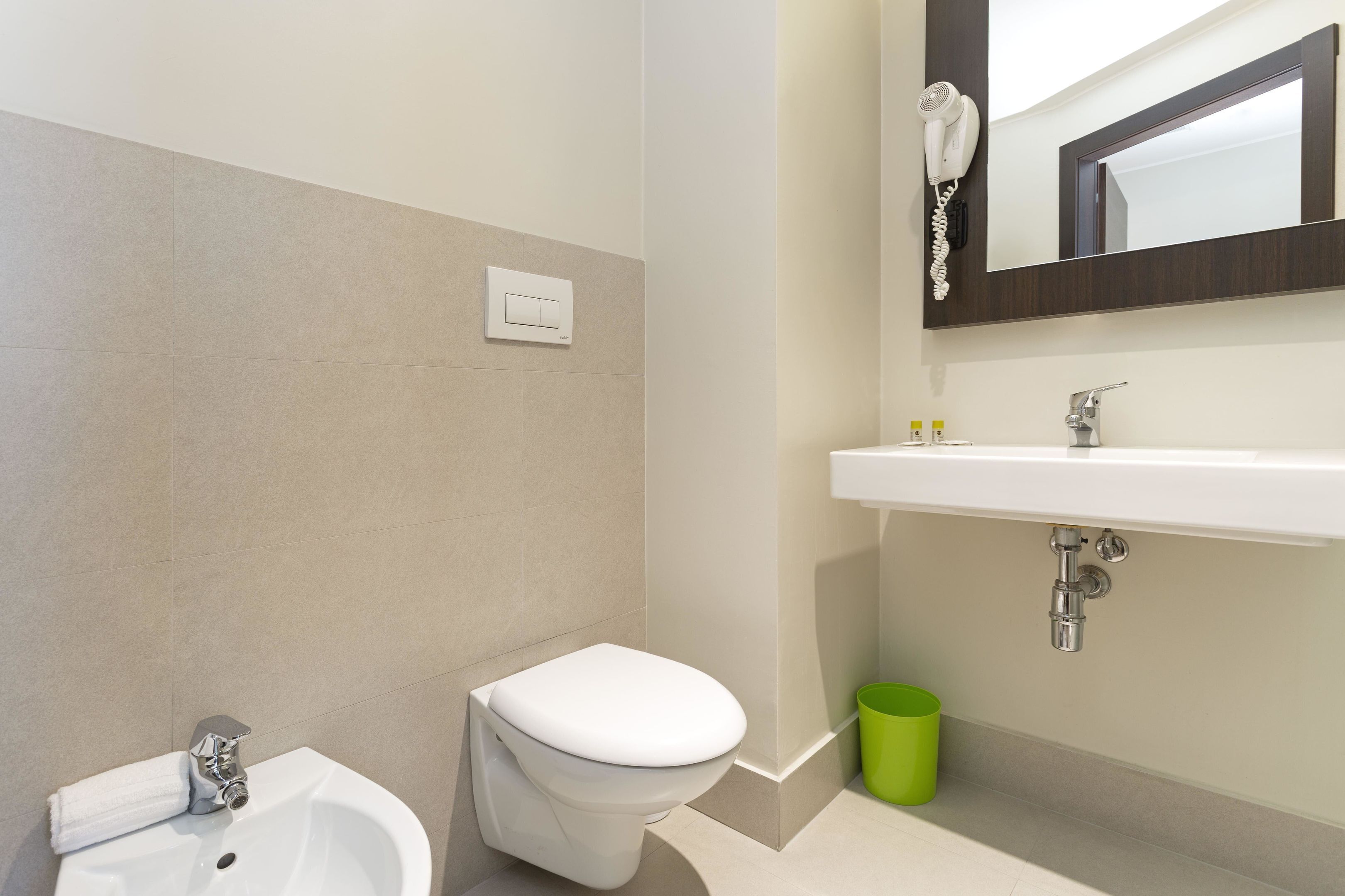 Un baño moderno con inodoro, bidé y lavamanos blancos.