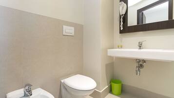 Un baño moderno con inodoro, bidé y lavamanos blancos.