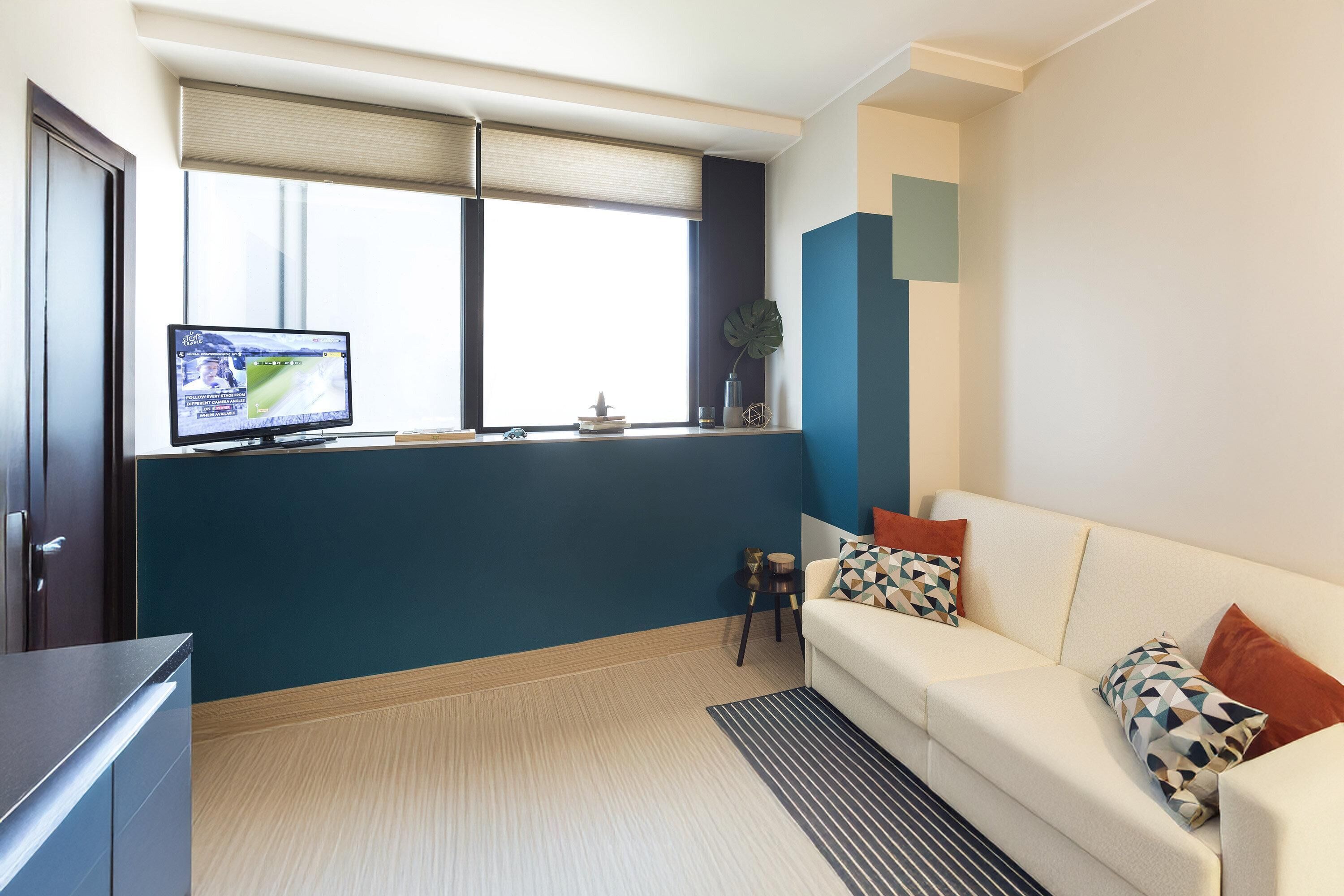 Uma sala de estar moderna com um sofá, uma televisão e uma janela com persianas.