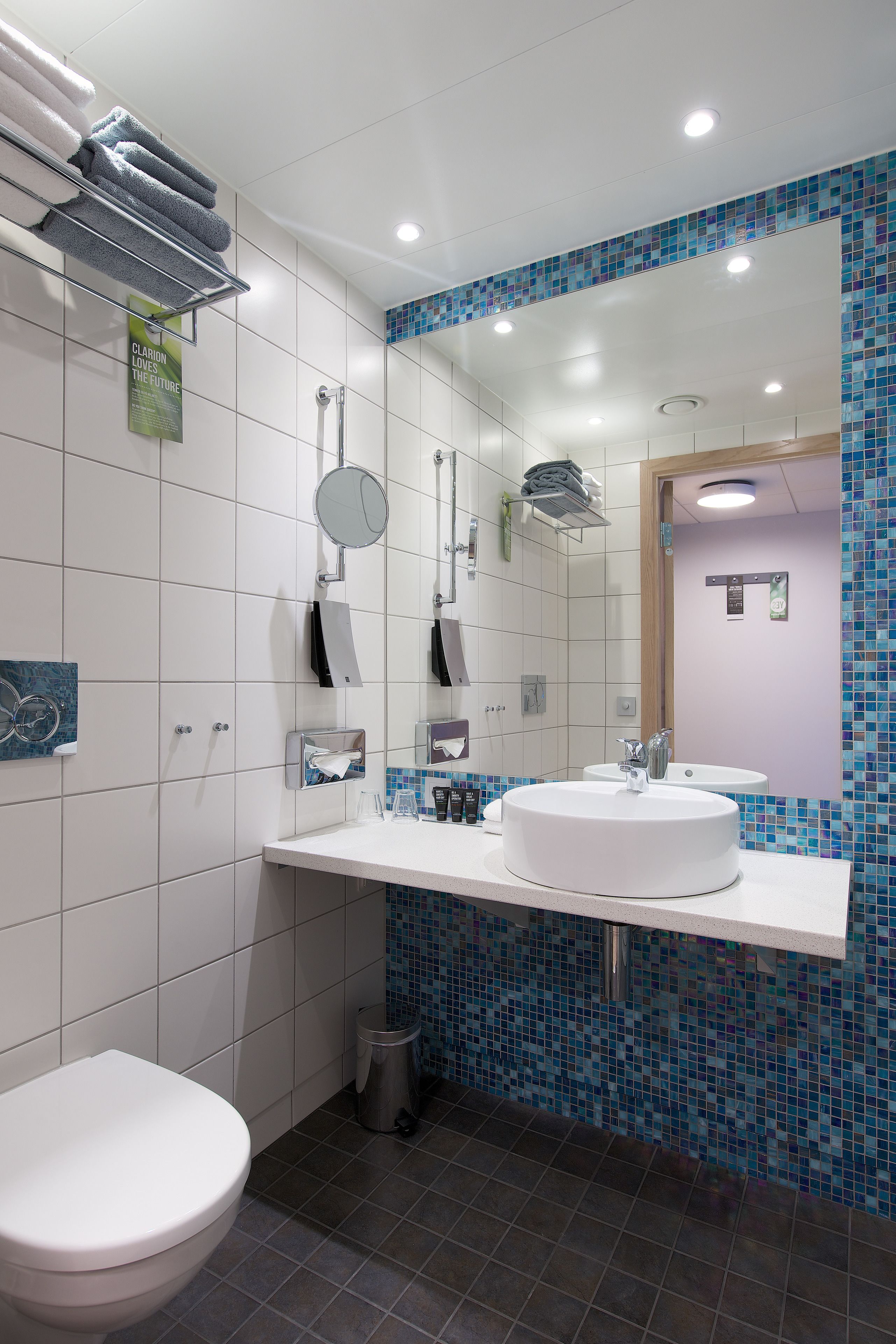 A modern bathroom with a white sink, mirror, and toilet.