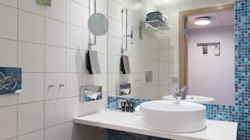 A modern bathroom with a white sink, mirror, and toilet.