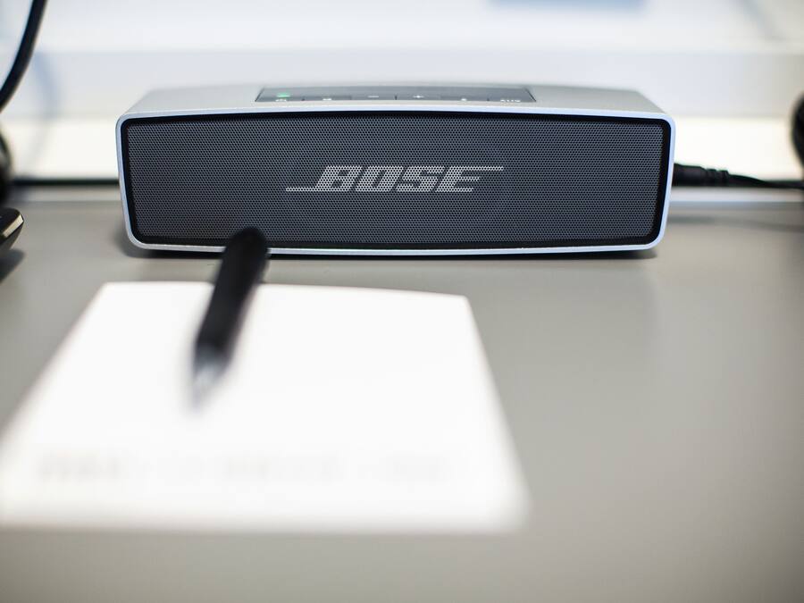 Un altavoz Bose sobre un escritorio, con un bolígrafo y una hoja de papel.