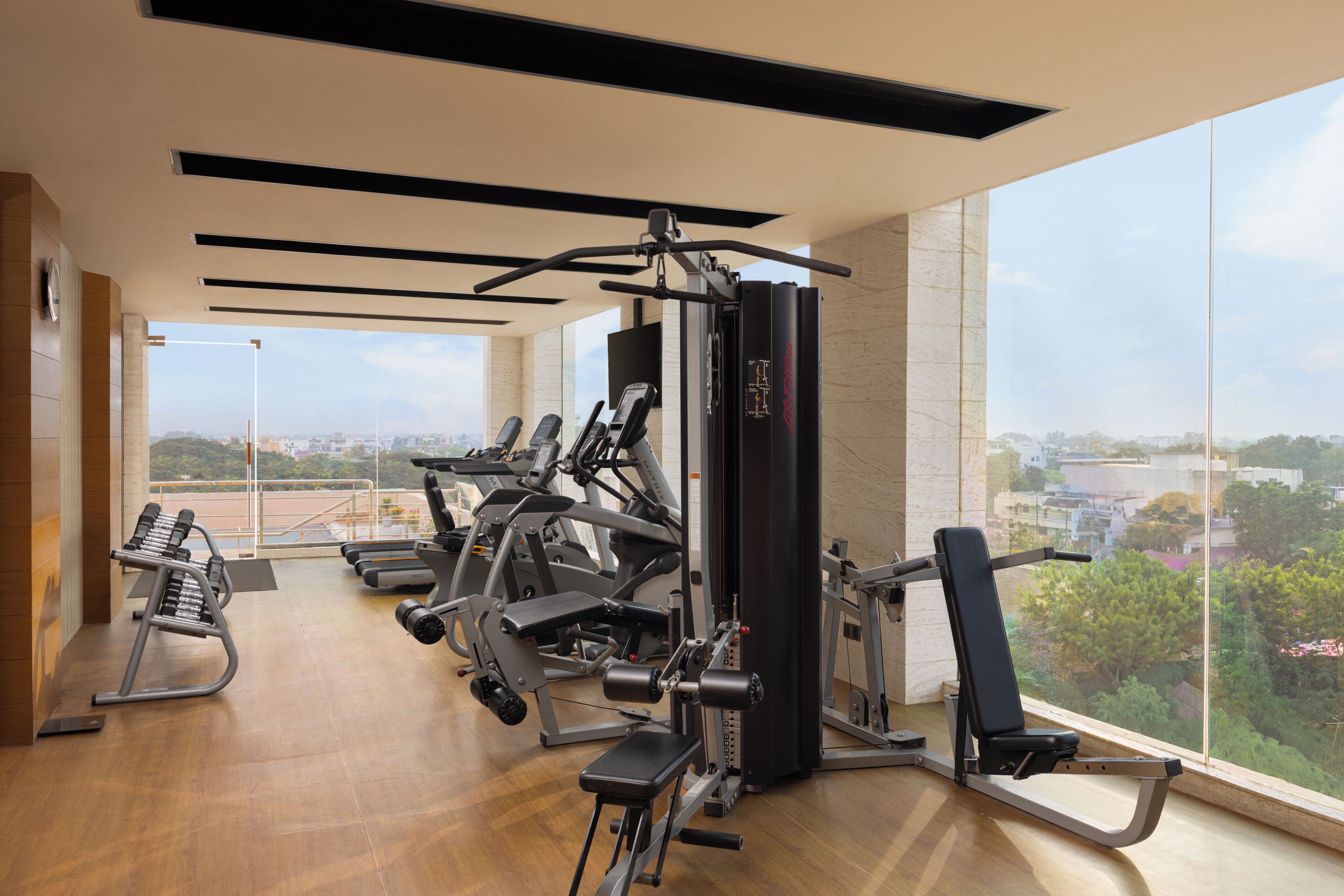 A gym with exercise equipment, a large window, and a view of the city.