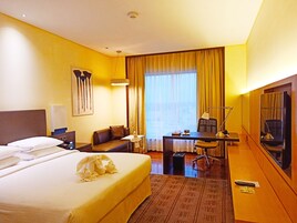 Una habitación de hotel con una cama grande, un escritorio con silla, televisión y ventana con cortinas.