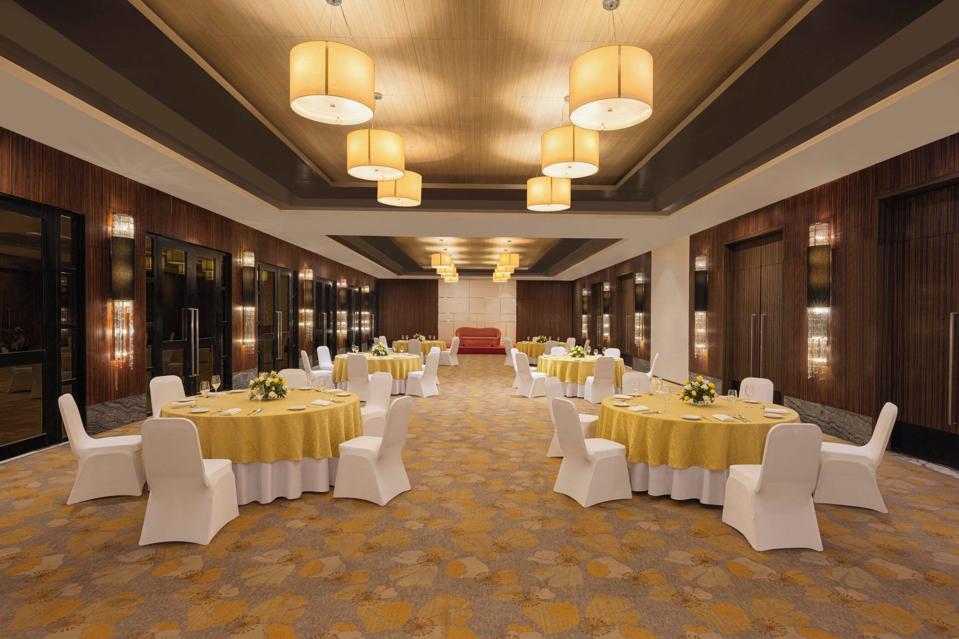 A conference room with round tables, white chairs, and a patterned carpet.