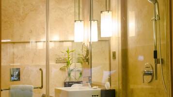 Un baño moderno con cabina de ducha de vidrio, un lavamanos con espejo y una banca.