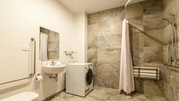 Un baño moderno con lavadora integrada, lavabo, inodoro y zona de ducha.