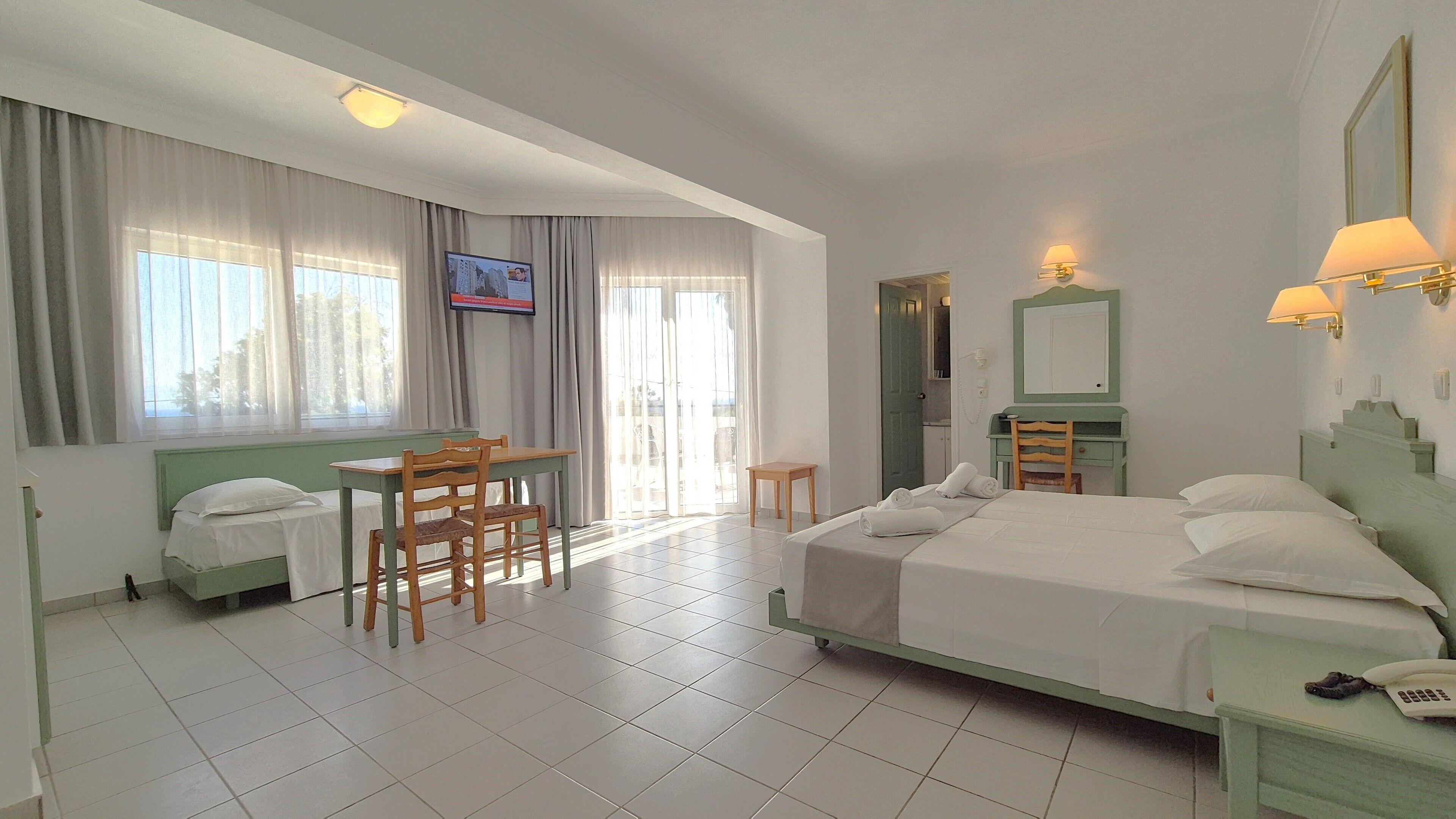 Ein Hotelzimmer mit Bett, Schreibtisch, Stuhl, Fernseher und Bad.