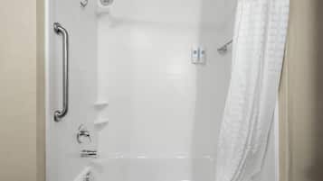 Ein schlichtes, weißes Badezimmer mit Badewanne, Duschkopf, Handlauf und Handtuchhalter.
