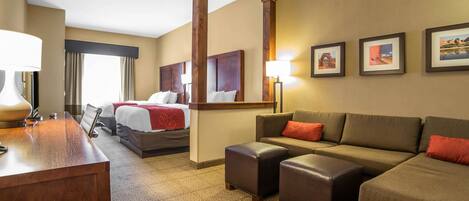 A hotel room with a bed, a sofa, a desk, and a mirror.