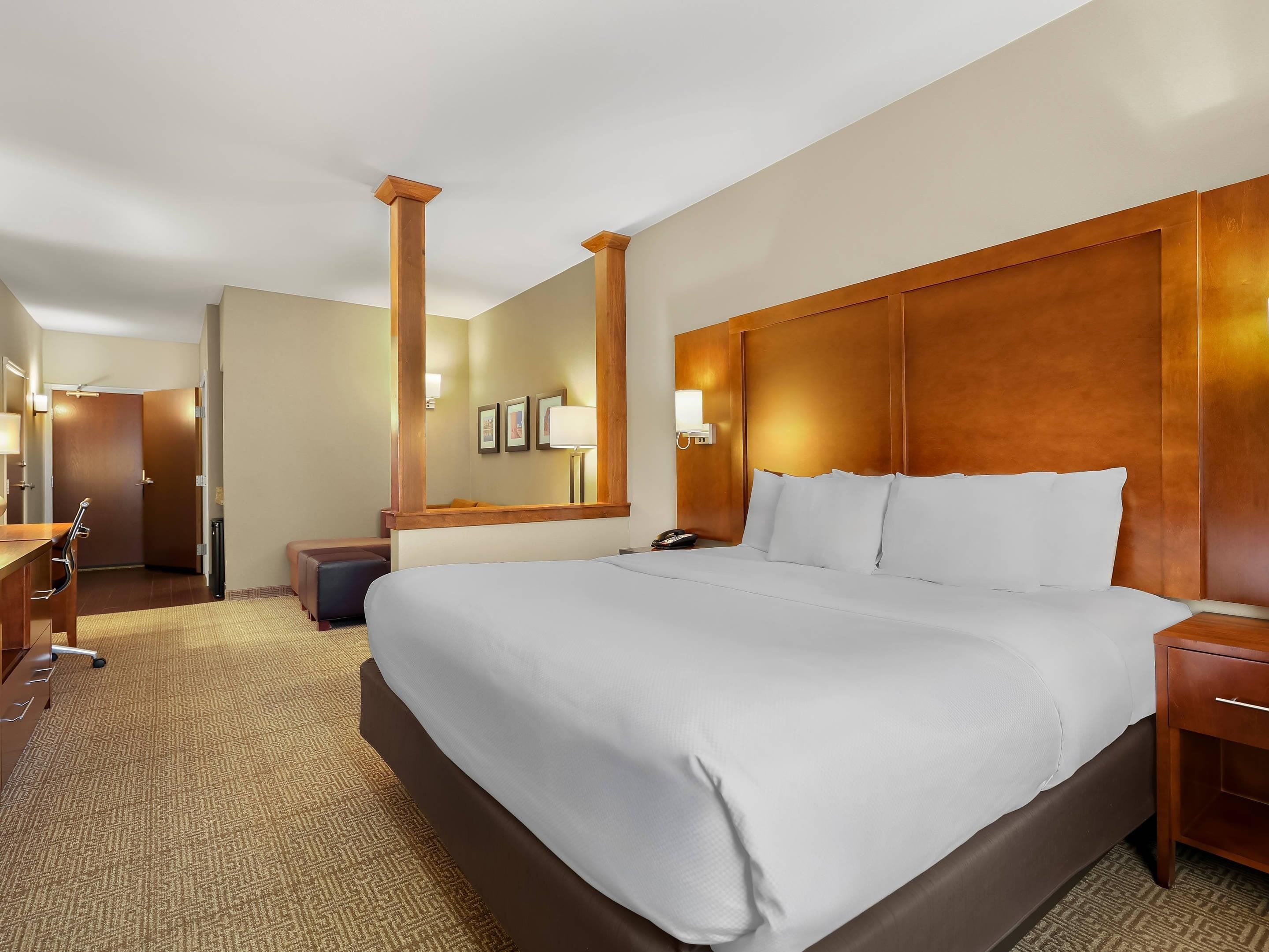 Ein Hotelzimmer mit einem großen Bett, einem Schreibtisch, einem Stuhl, einem Kleiderschrank und einem Spiegel.