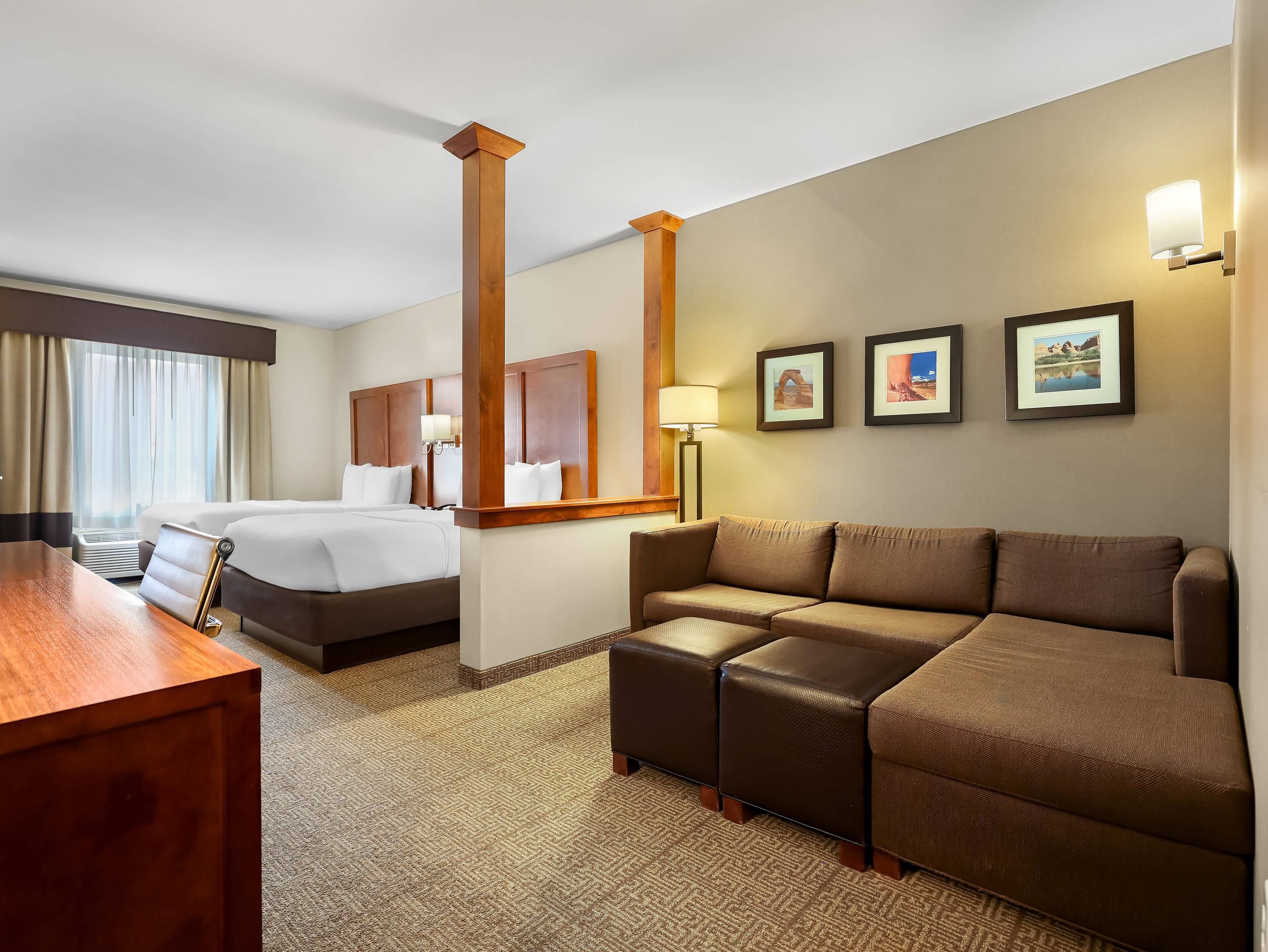 A hotel room with a bed, a sofa, a desk, and a large mirror.
