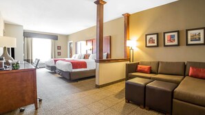 Una habitación de hotel con cama, escritorio, sofá y un espejo grande.