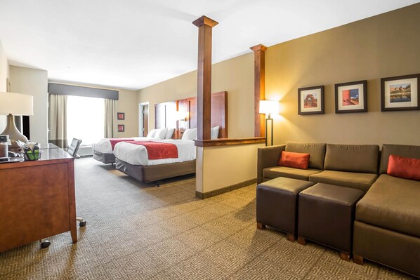 A hotel room with a bed, a desk, a sofa, and a large mirror. - Comfort Suites Moab near Arches National Park (Moab)