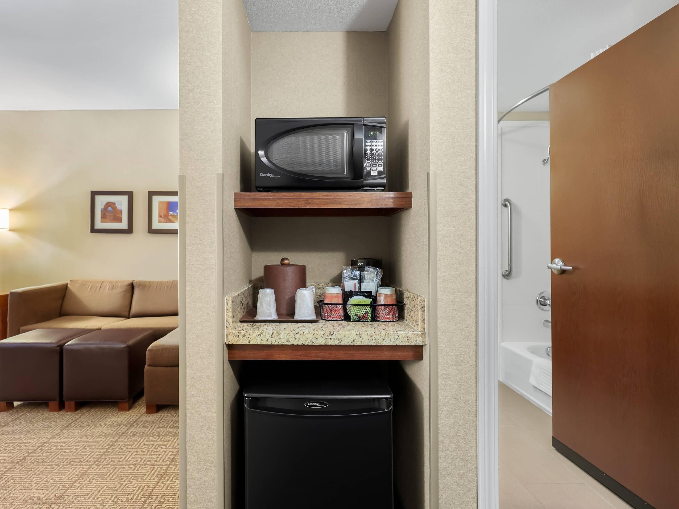 Ein kompaktes Hotelzimmer mit Küchenzeile, einer Mikrowelle, einer Kaffeemaschine und einem Mülleimer.